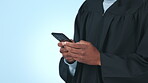Graduate, college student and hands typing on a phone in studio for communication or chat. University graduation, education mockup and person on smartphone for social media message on blue background