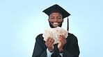 Smile, money and education with a black man graduate on a blue background in studio as a winner. Cash, finance or investment and a happy young university student at graduation with a savings bonus