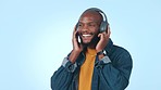 Black man, headphones and energy with dancing and music, happy and care free isolated on blue background. Mockup space, listening to radio and audio streaming with techno or disco in a studio