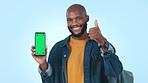 Green screen, thumbs up and man with phone in studio with mockup for advertising or marketing. Smile, tracking markers and portrait of African person pointing to cellphone and agreement hand gesture.