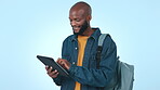 Tablet, education or social media with a black man student on a blue background in studio for study research. Learning, technology or app with a young university or college pupil reading information