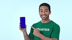 Blue screen, phone and man volunteer pointing to mockup space for marketing, promotion or advertising. Tracking markers, cellphone and portrait of Indian male community worker by studio background.