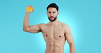 Portrait, health and a man with an orange on a blue background with muscle, exercise and wellness. Happy, food and a fitness coach or strong model with fruit for workout, nutrition or diet training
