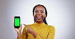 Woman, face and phone green screen for marketing mockup, presentation or happy news in studio. Excited african person pointing to mobile with design opportunity, tracking marker and white background