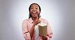 Woman, popcorn and laughing portrait in studio while watching a comedy or funny movie. Excited african female person pointing  with a snack box on a grey background for joke, gossip or cinema film