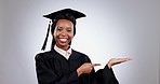 Graduate, black woman and pointing at hand space in studio isolated on a white background. Face portrait, palm and graduation student in presentation of mockup, advertising and marketing of smile.