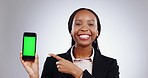 Green screen, phone and hand pointing by woman face in studio for social media, news or review on grey background. Smartphone, mockup and portrait of lady model show platform, sign up or contact info