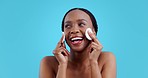 African woman, cotton pad and skincare in studio, cleaning face or happy with results by blue background. Girl, model or smile with natural beauty, glow or cosmetic change with self care for wellness