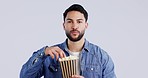 Eating popcorn, man and watching tv or movie with snack, theater food and streaming series in studio. Grey background, happy male person and hungry with television, cinema film or video of show