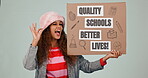 Perfect, wink or education and a woman student on a gray background in studio with a cardboard poster. Portrait, politics or government and a young university pupil in protest for quality school