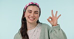 Okay hands, face and woman in studio for vote, certified review or feedback on blue background. Portrait, happy model and ok for success, agreement or icon of support, yes emoji or sign of excellence