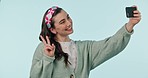 Happy woman, thumbs up and peace sign in selfie, photography or social media against a studio background. Female person smile, like or emoji for picture photograph or online vlog and memory on mockup