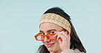 Fashion glasses, face and woman wink, blink and confident in retro clothes, trendy apparel or outfit. Flirty eye contact, retail style and portrait of model with studio sunglasses on blue background
