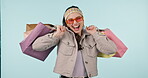 Shopping bag, portrait and studio woman excited for retail fashion spree, sales market or Black Friday deal, promotion or discount. Dancing, commerce clothes purchase or customer on blue background
