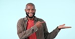 Pointing, face or happy black man by offer, discount deal or retail sale on studio space or logo advertising. Smile, hand palm or excited person with mockup, news or menu promotion on blue background
