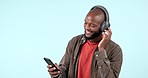 Headphones, mobile app or happy black man listening to music for freedom in studio on blue background. Smile, search or African person streaming a radio song, sound or audio on an online subscription