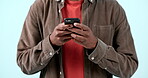 Hands, phone and man typing in studio isolated on blue background. Smartphone, closeup and person scroll on internet search app, social media networking and online communication on digital technology