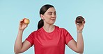 Woman, apple and donut in diet choice, eating or health and wellness to lose weight against a studio background. Fitness, female person and biting natural organic fruit for nutrition on mockup space