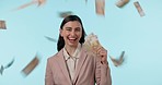 Smile, lottery and raining money with a woman winner in studio on a blue background for financial freedom. Portrait, happy and a rich or wealthy person looking confident with finance or accounting