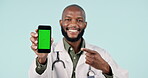 Happy black man, doctor and phone with green screen, mockup or advertising against a studio background. Portrait of African male person pointing to mobile smartphone display, app or tracking markers