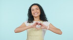 Heart hands, love and a young woman in studio with care, emoji and kindness. Face of a gen z girl with gesture, icon and portrait on a blue background for thank you, charity support and review