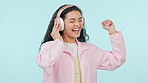 Music, dancing and excited woman on headphones in studio isolated on blue background. Radio, happy person moving with energy to audio and listening to sound, hearing hip hop for freedom or streaming