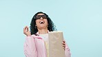 Popcorn, laughing or happy woman watching movie in studio for television or cinema to relax. Comedy, throw or funny person eating snack for streaming film, subscription or 3d tv on blue background