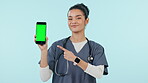 Happy woman, nurse and phone and pointing to green screen in advertising on mockup against a studio background. Portrait of female person or medical doctor showing mobile smartphone app or display