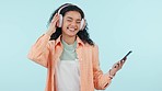 Woman, headphones and dance with smartphone in studio to celebrate freedom, party or audio on blue background. Happy model listening to groovy music with cellphone, hearing radio or sound with energy