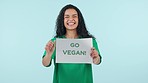 Happy, vegan and face of woman with sign, poster and eco friendly diet for animal rights or protest in studio. Climate change, activist or portrait of volunteer with billboard on blue background