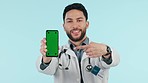 Doctor, phone green screen and choice, healthcare info or presentation of sign up or registration in studio. Face of medical man on mobile mockup, pointing you and tracking marker on blue background