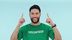 Smile, studio man and volunteer pointing up at non profit direction, climate change support or NGO community service. Activism kindness, charity foundation news and portrait person on blue background