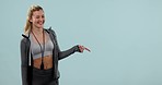 Fitness, happy face and woman pointing at mockup space in studio isolated on a blue background. Portrait, athlete advertising and marketing workout of coach or personal trainer on presentation list