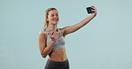 Gym selfie, woman and water in studio, health and wellness for social media post and influencer on blue background. Fitness, workout and smile in picture, memory and mockup space with drink in bottle