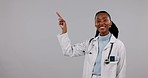 Black woman, doctor and pointing to mockup in advertising against a studio background. Portrait of happy African female person, medical or healthcare worker showing notification, list or information