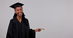 Happy black woman, graduation and pointing on mockup in advertising against a studio background. Portrait of African female person, student or graduate showing list, qualifications or information