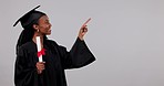 Black woman, graduation and pointing on mockup with certificate in advertising against a studio background. Portrait of African female person or student graduate showing list, qualification or degree