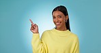 Face, woman and advertising presentation in studio of deal, information and choice on blue background. Happy portrait, indian model and pointing to mockup space, announcement and launch of promotion