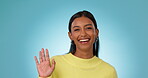 Face, smile and woman with greeting, wave and communication on a blue studio background. Portrait, person and happy model with hand gesture, sign language and hello with welcome, smile and thank you