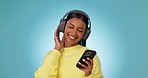 Dance, headphones and woman with phone in studio to celebrate freedom, party and audio on blue background. Happy indian model listening to groovy music with mobile, hearing radio or sound with energy