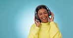 Dance, happy woman and music headphones in studio for celebration of freedom, party or hearing audio song on blue background. Excited indian model listening to multimedia, sound or radio subscription