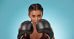 Boxing, athlete and portrait of boxer fight training with gloves isolated in a studio blue background for exercise. Fitness, workout and young woman with energy for health and wellness in MMA