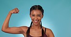 Arm, smile and kiss with a woman personal trainer in studio on a blue background for fitness success. Portrait, smile and exercise with a happy young sports person flexing her bicep for motivation
