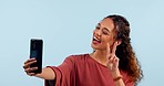 Woman, selfie and studio for blowing kiss, smile or hand icon for memory on web blog by blue background. Influencer girl, peace sign and photography for funny face, live stream or social media post