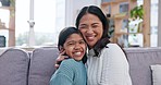 Family, face and mother kiss girl child on a sofa with care, smile and bonding in their home together. Portrait, love and mom embrace kid in a living room with trust, security or comfort in a house