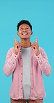 Happy, face and man pointing up in studio for news, announcement or notification on blue background. Excited, smile and guy model with hand sign show space, service or opportunity, sign up or offer