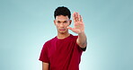 Hand, stop and warning with a serious man on a blue background in studio to gesture rejection. Portrait, emoji and palm of a moody young person looking to deny or refuse with a sign of defence