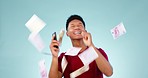 Cash rain, smartphone and man, winning competition online or social media giveaway with excited and happy dance. Celebration, money prize in air and lottery with app in studio on blue background