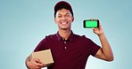 Phone, green screen and delivery man in a studio with a cardboard box for ecommerce package. Tracking markers, chorma key and portrait of male courier with cellphone mockup space by blue background.
