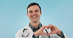 Heart, sign and portrait of doctor with support or love hand gesture with smile isolated in studio blue background. Healthcare, professional and portrait of medical employee with emoji for cardiology